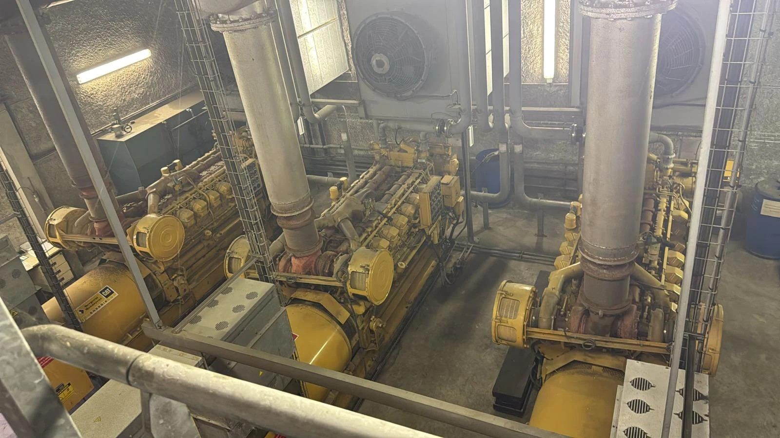 Vue depuis une passerelle sur trois groupes électrogènes Caterpillar installés en sous-sol