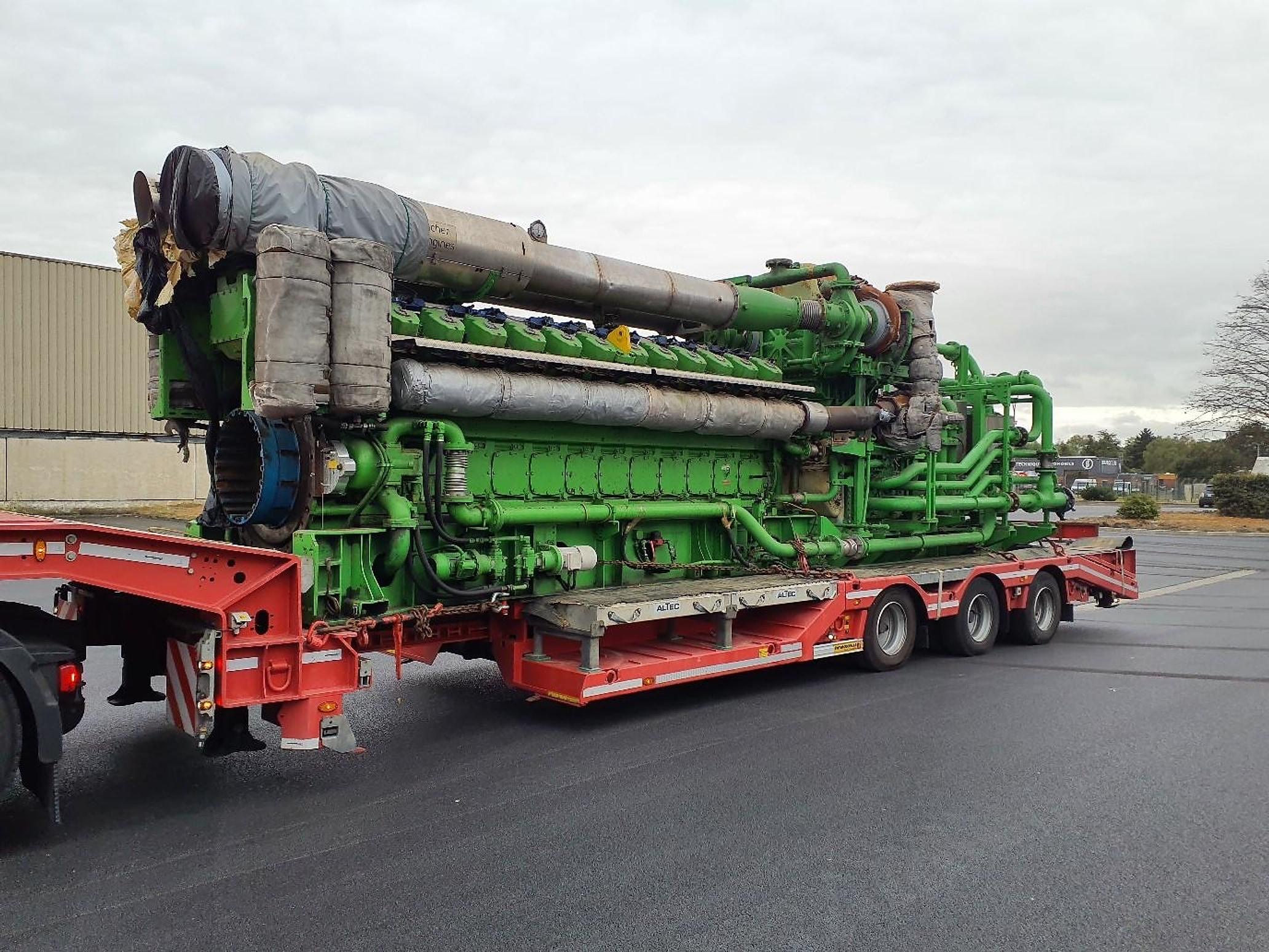 Moteur à gaz industriel de grande puissance, peint en vert, chargé sur une semi-remorque surbaissée rouge